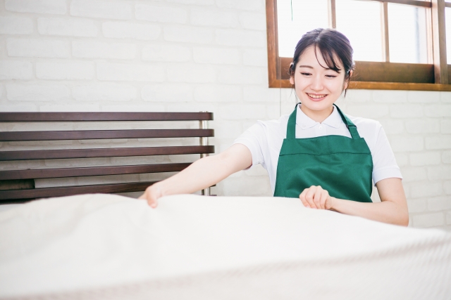 ベッドメイキングする家事代行の女性