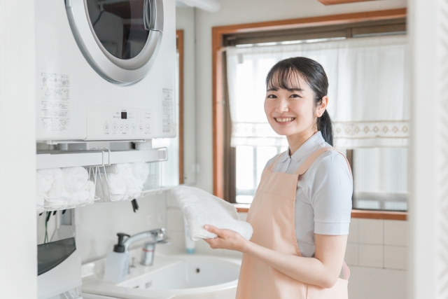 洗濯機で布製品を洗っている女性の写真