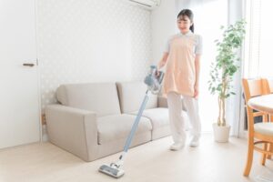リビングで掃除機をかけて部屋を清潔に保つ女性