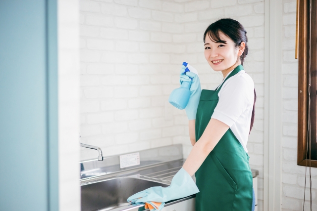 キッチンでスプレーを使って掃除する清掃スタッフの女性
