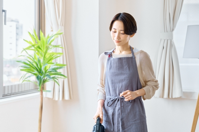 窓のそばで部屋を掃除している女性