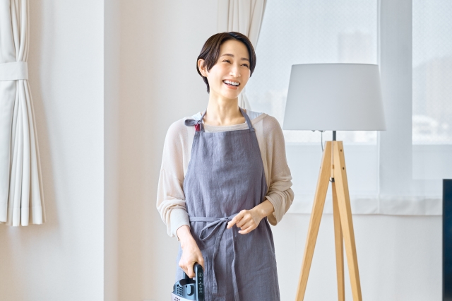 エプロン姿で室内に立つ清掃スタッフの女性