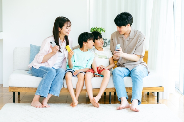 リビングで笑顔の家族が団らんする様子