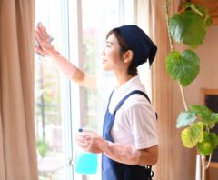 窓を掃除する女性の後ろ姿