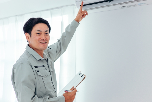 エアコン内部を点検・説明する作業員男性