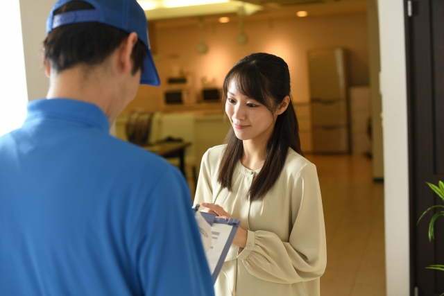 作業員が玄関先で女性と挨拶しているシーン