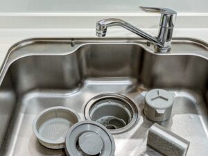 シンクの中に外した排水トラップ部品が並ぶ様子