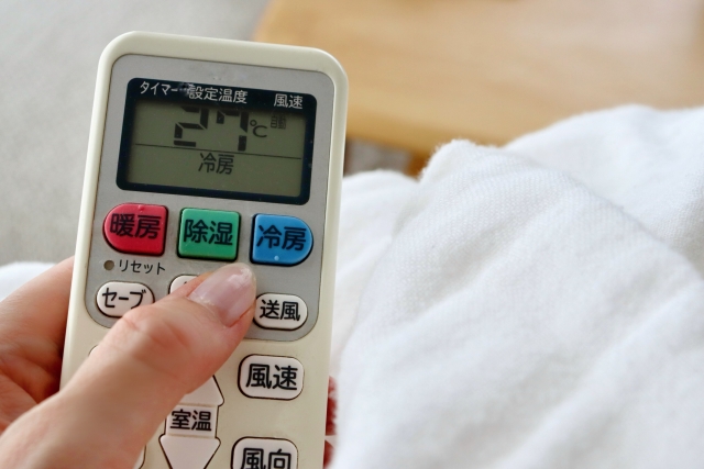 リモコンでエアコンの動作確認をしている手元
