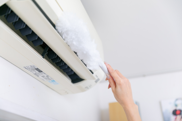 エアコンクリーニングの時期を調べつつ掃除をする人の手
