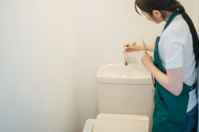 トイレタンク周りを掃除している清掃スタッフ