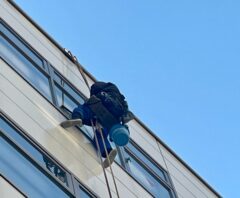 建物外側をロープで移動しながら窓掃除を行う作業員