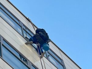 建物外側をロープで移動しながら窓掃除を行う作業員