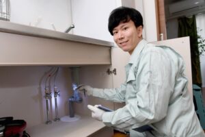 キッチンの排水口を点検する作業員