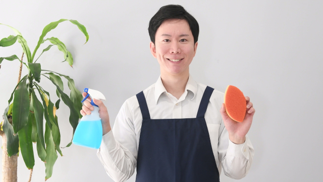 清掃用具を持った笑顔の清掃スタッフ
