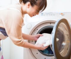 ドラム式洗濯乾燥機のクリーニング業者を待ちながら洗濯をする女性