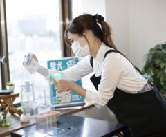 店舗の窓ガラスを丁寧に拭く女性スタッフ