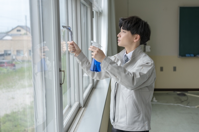 室内の大きな窓ガラスを拭いている清掃作業員
