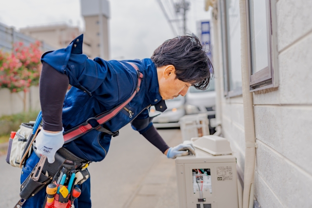 エアコン室外機を高圧洗浄する作業員