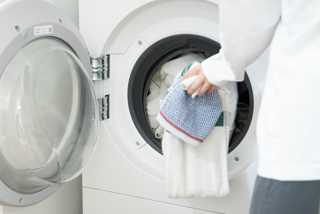 ドラム式洗濯機の扉まわりを布で拭いて掃除している様子