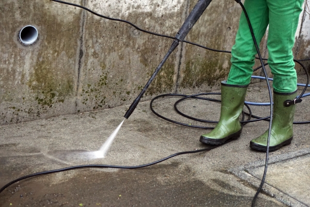 高圧洗浄機でコンクリートの汚れを洗い流している様子