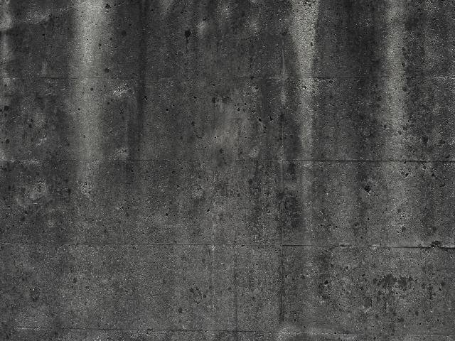 雨だれや汚れで黒ずみが目立つコンクリート壁